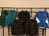 Front view of all six outerwear pieces including three vests, two jackets, and one sweatshirt.