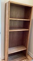Front angled view of wooden bookshelf showing multiple shelves and natural wood finish.