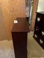 Side angled view of the dark wood organizer showing its rectangular shape and smooth dark finish.