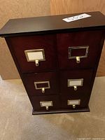 Front view of the dark wood organizer showing six drawers with brass pulls and label holders, dark wood finish with visible wear.