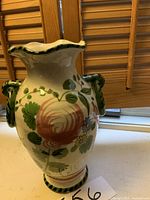 Front view of the ceramic vase showing floral decorations and scalloped rim