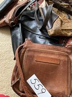 Four women's handbags shown together. Brown leather Fossil bag seen in front with a label number 559.