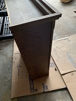 Side view of the dark wooden cupboard showing its depth and wood grain