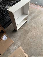 White wood shelving unit with two shelves and towel holder rod, showing front and side view