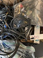 Photo showing a tangle of various AC-DC adapters and cables including some in plastic bags.