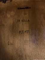 Close-up photo of Ethan Allen brand marking and item number stamped on wood surface.