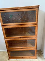 Front view of oak lawyer's style bookcase with four glass doors, top door with stained glass design
