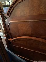 Close-up of the headboard showing wood grain and decorative molding with wear marks.