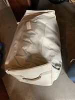 Closed carrying case for Aero bed, white or beige, rectangular with a handle showing some dirt or stains.