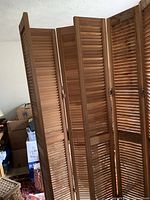 Photo of one wooden 3-panel louvered room divider set up upright showing the panels and hinges