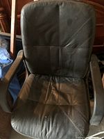 Front view of black office chair with visible wear and marks on padded seat and backrest