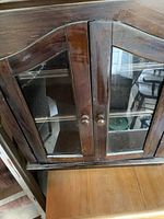 Front view of dark wood cabinet showing glass inset doors and interior shelves.