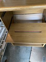 Close-up of wooden sliding shelf with slot on printer table.