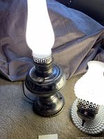 Tall electric lamp with milk glass chimney and a white hobnail milk glass wall lamp on carpet