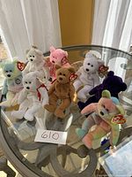 Overview photo of eight Ty Beanie Babies bears displayed on a glass table, showing different colors and designs with original tags attached.