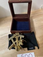 Opened teak box lined with blue felt, containing brass sextant and NoIR pouch.