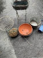 Overview of assorted yard ornaments including plant stands, pots, and metal containers on pavement