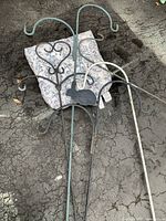 Five metal shepherd hooks of varying colors and styles on asphalt surface