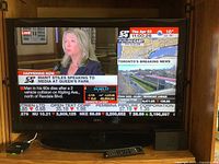 40 inch Seiki flat screen TV powered on showing news channel, in wooden media cabinet, with visible remote.