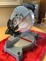 Full view of Delta miter saw on red cloth backdrop