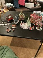Overview of all Christmas village buildings, figurines, and accessories arranged on a table.