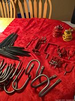 Overview of various metal hooks and brackets laid out on a red surface including L brackets, U hooks, screw-in hooks, and coil-shaped hooks.