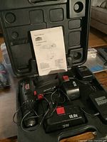 Image showing Jobmate cordless drill, two battery packs, battery charger and owner's manual inside original hard plastic case.