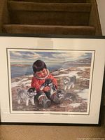 Front view of framed signed print showing child with puppies in an outdoor setting