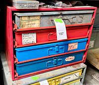 Front view of red metal cabinet with four drawers filled with assorted hardware