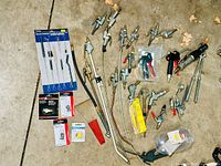 Overview of the air tool attachments laid out on the floor including multiple air blow guns with nozzles, metal extension tubes, packed adapters and cleaning brushes.