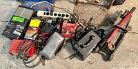 Overview of items showing hydraulic car jack, battery boosters, battery charger, and other equipment with cables on concrete floor