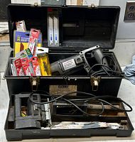 Corded reciprocating saw and multiple blade packs inside black storage case, showing condition and included items.
