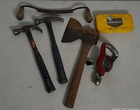 Photo of all items including two hammers, hatchet, drawknife, hand drill, and Grizzly faucet washers tin.