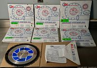 Photo showing six boxed Diamond Systems Inc. diamond saw blades stacked and laid out along with one loose saw blade and instruction leaflet.