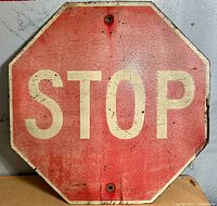 Front of the stop sign showing the red background with white STOP text and aged patina.