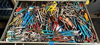 Top-down view of open drawer filled with mixed pliers and wrenches