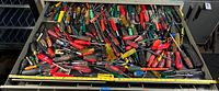 Wide view of toolbox drawer contents showing many screwdrivers in various colors and handle types with tape measures for scale.