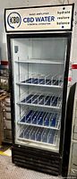 Front view of single door upright fridge cooler with CBD Water branding light panel and blue vertical dividers on shelves inside.