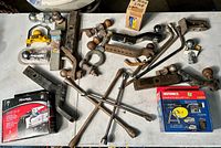 Full lot overview showing various trailer hitches, hitch balls, locks, and accessories laid out on a white table.