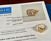 Appraisal certificate laid flat with ring positioned at lower right, showing printed appraisal title, date, client reference, and ring.