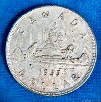 Obverse side of the coin showing two men in a canoe with 'CANADA' and '1935' inscriptions.
