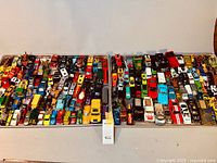 Two large aluminum trays filled with a multitude of diecast toy vehicles in various colors and styles.