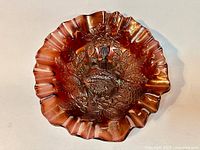 Top-down view of ruffled rim iridescent carnival glass bowl with visible peacock and urn embossing