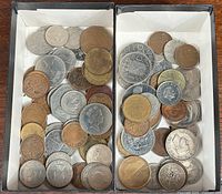 Top view of two compartments filled with many various international coins of different sizes and colors.