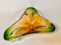 Top view showing yellow, clear, and green hand blown Murano glass ashtray with three rounded lobes and a glossy finish.