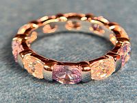 Close-up side angle showing the silver band and alternating blue and clear oval cubic zirconia stones with rhodium plating.