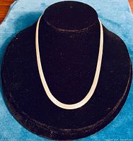 Necklace displayed on black bust against blue cloth, front view