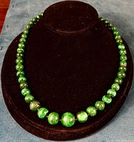 Front view of vintage graduated Malachite necklace on black display stand showing graduated round beads and clasp.