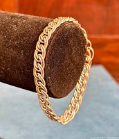 Heavy, thick 925 sterling silver vintage link bracelet shown draped over brown velvety bracelet holder, highlighting detailed interwoven link design.
