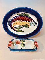 Full view of the large fish platter and small floral dish side by side on stand.